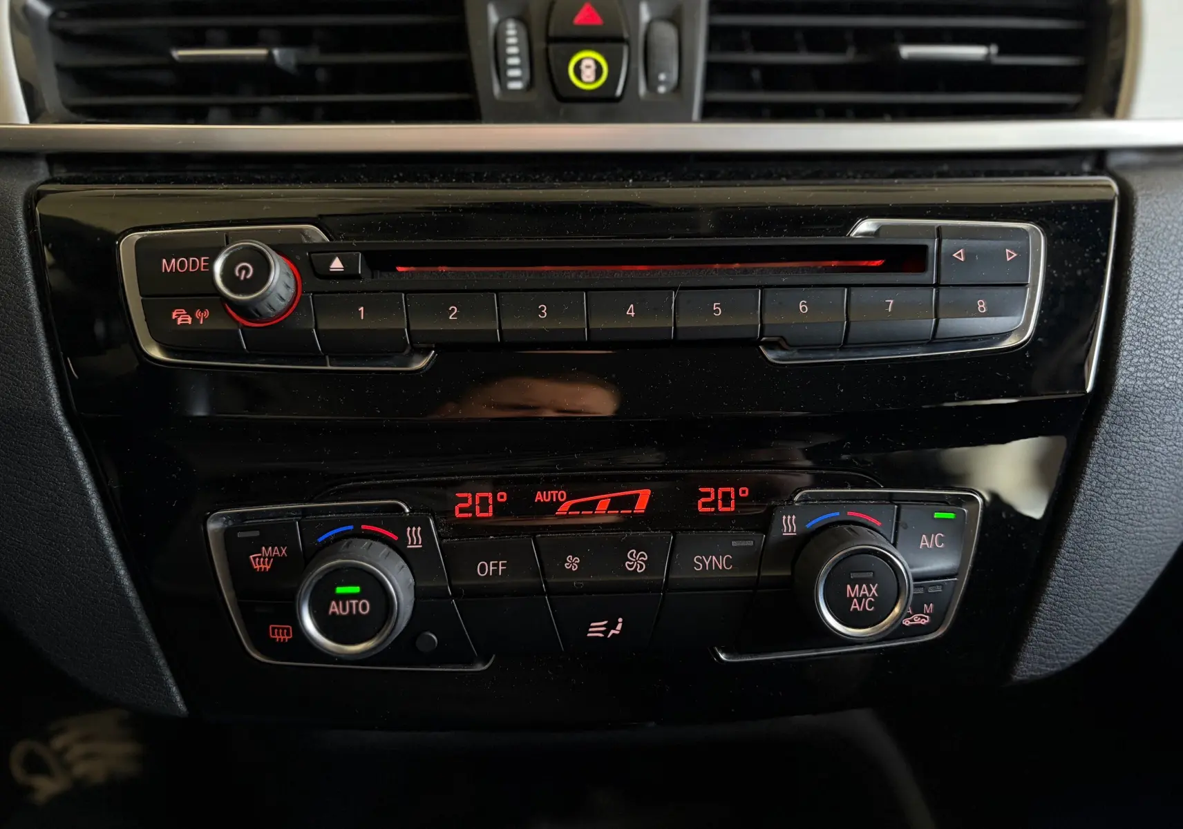 Gros plan sur la console centrale noire du BMW X1 20i S-DRIVE SPORT LINE, avec commandes climatisation digitale et boutons radio.