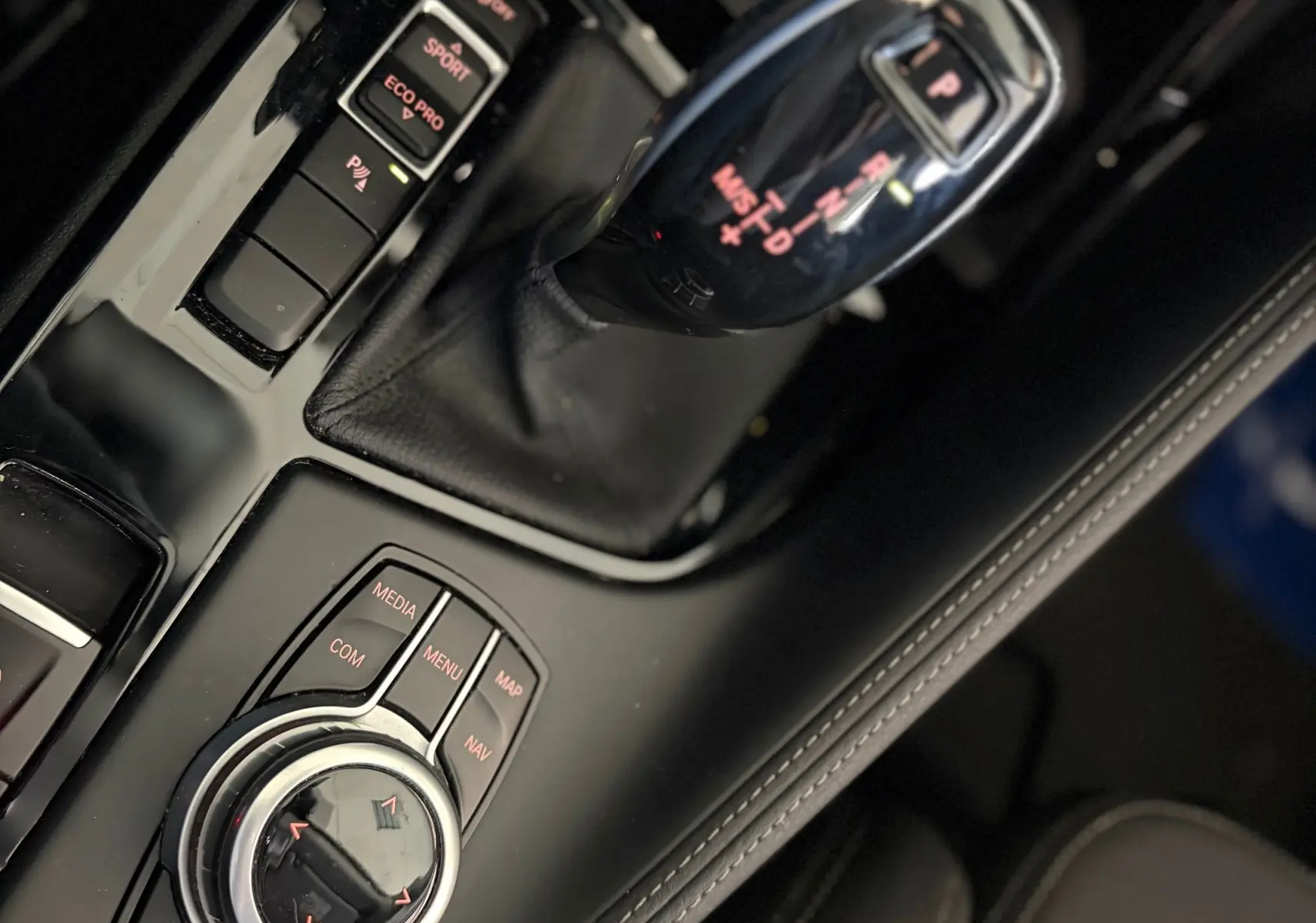 Vue rapprochée de la console centrale noire du BMW X1 20i S-Drive Sport Line 2018, avec levier de vitesse automatique et commandes multimédia.