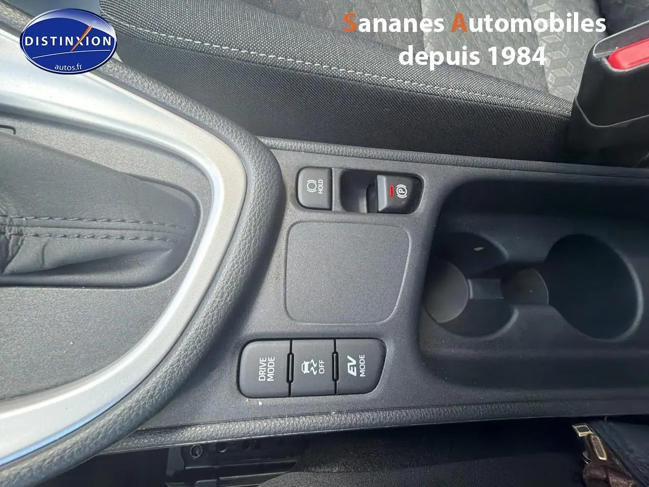 Gros plan sur la console centrale noire de la Toyota Yaris Hybrid 2023, montrant les boutons Drive Mode, EV Mode et frein de parking électronique.