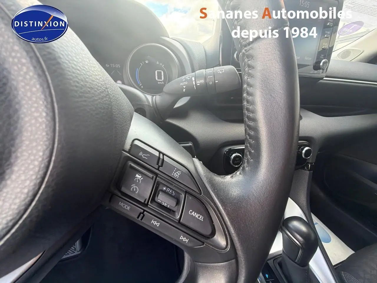 Vue rapprochée du volant de la Toyota Yaris Hybrid 2023, montrant les commandes intégrées et la console de boîte automatique.