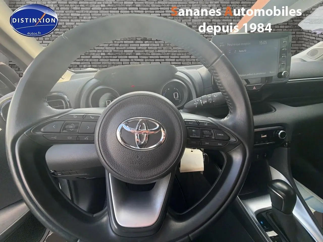 Vue intérieure centrée sur le volant noir de la Toyota Yaris Hybrid 2023 avec tableau de bord et écran tactile visible.
