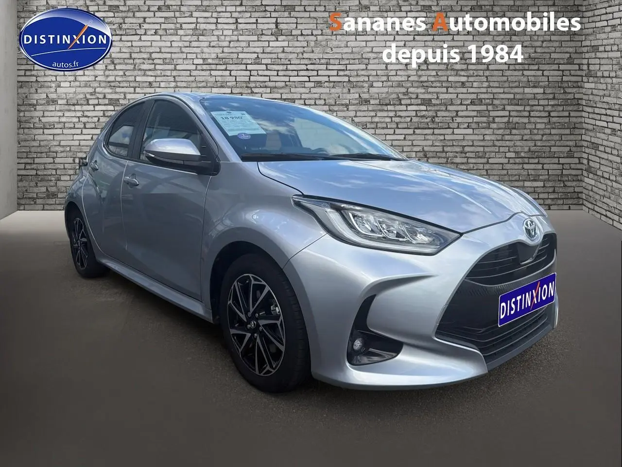 Toyota Yaris Hybrid 2023 gris métallisé en 3/4 avant droit avec jantes alliage bi-ton et vitres surteintées.