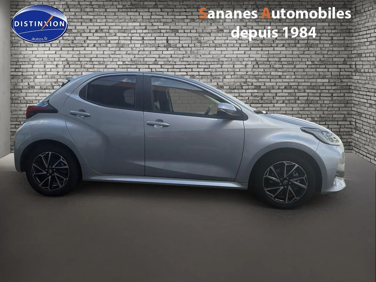 Profil droit d'une Toyota Yaris Hybrid 116h 2023 gris métallisé avec jantes alliage bi-ton et vitres arrière surteintées.