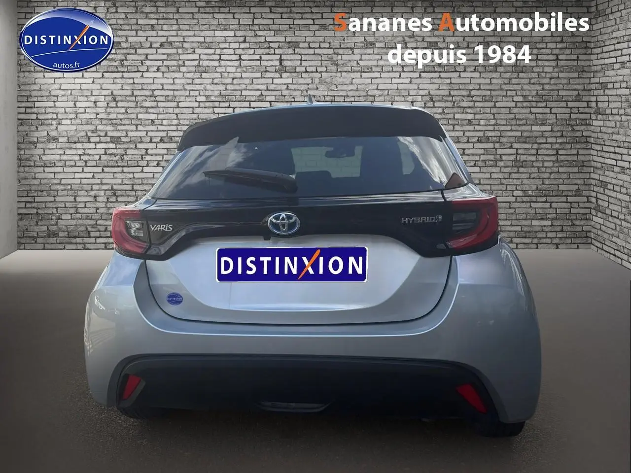 Vue arrière d'une Toyota Yaris Hybrid 116h 2023 en peinture métallisée INC avec toit noir et feux arrière distinctifs.