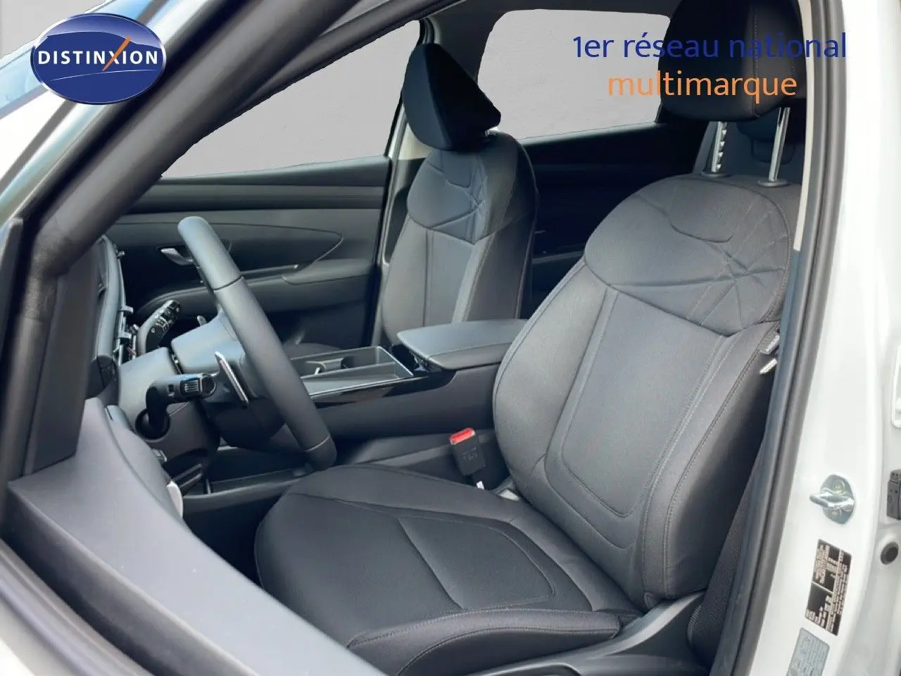 Intérieur avant droit du Hyundai Tucson blanc Atlas 2026, sièges tissu noir et volant multifonction cuir.
