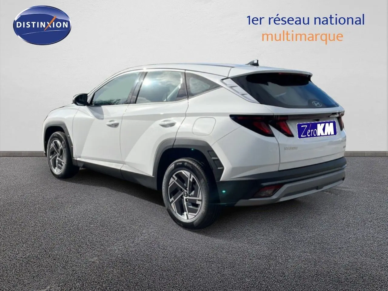 Vue 3/4 arrière gauche d’un Hyundai Tucson blanc Atlas 2026 avec jantes bi-ton et vitres teintées.