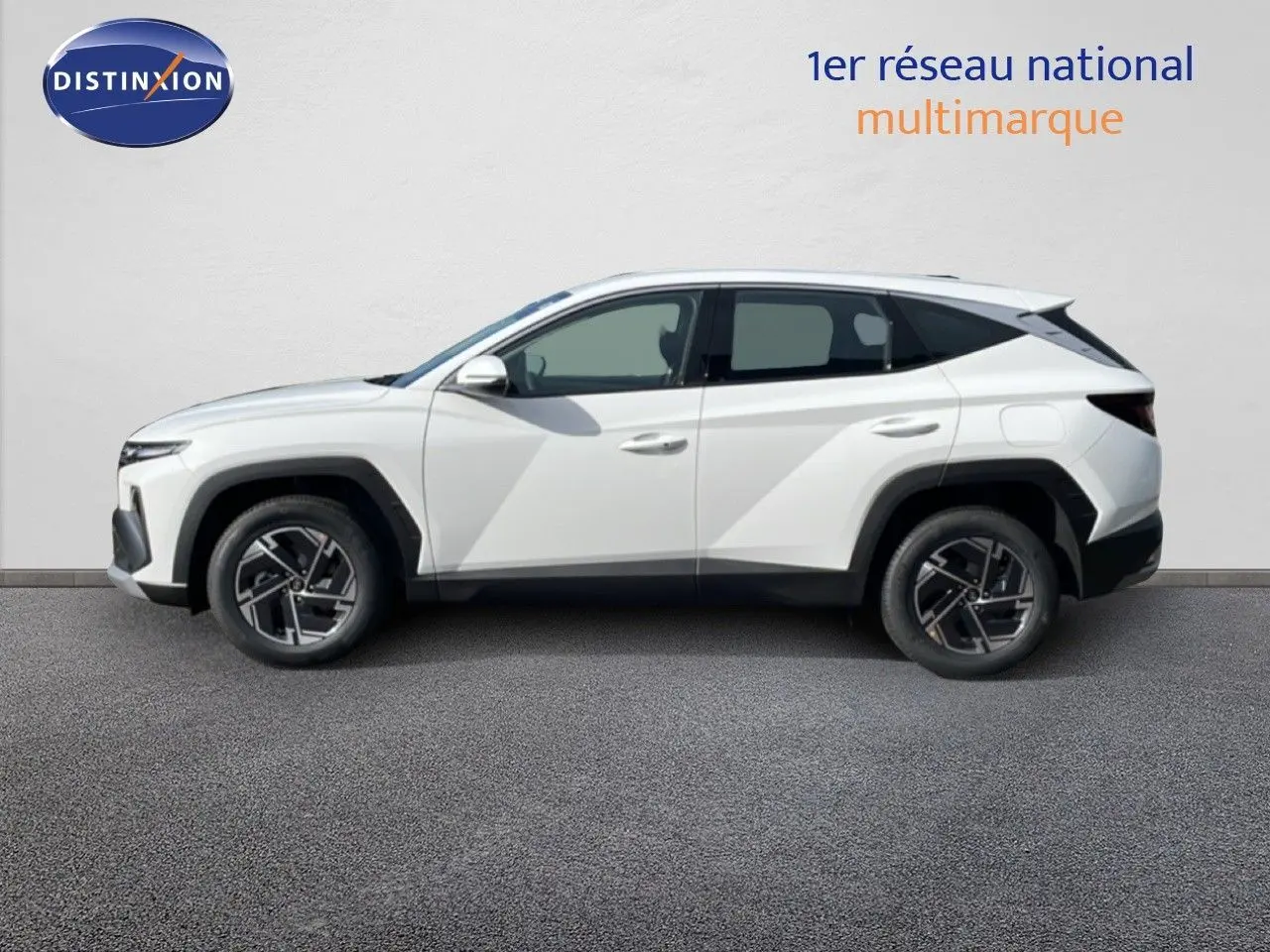 Profil droit d'un Hyundai Tucson blanc Atlas 2026, version hybride avec jantes bi-ton et lignes anguleuses marquées.