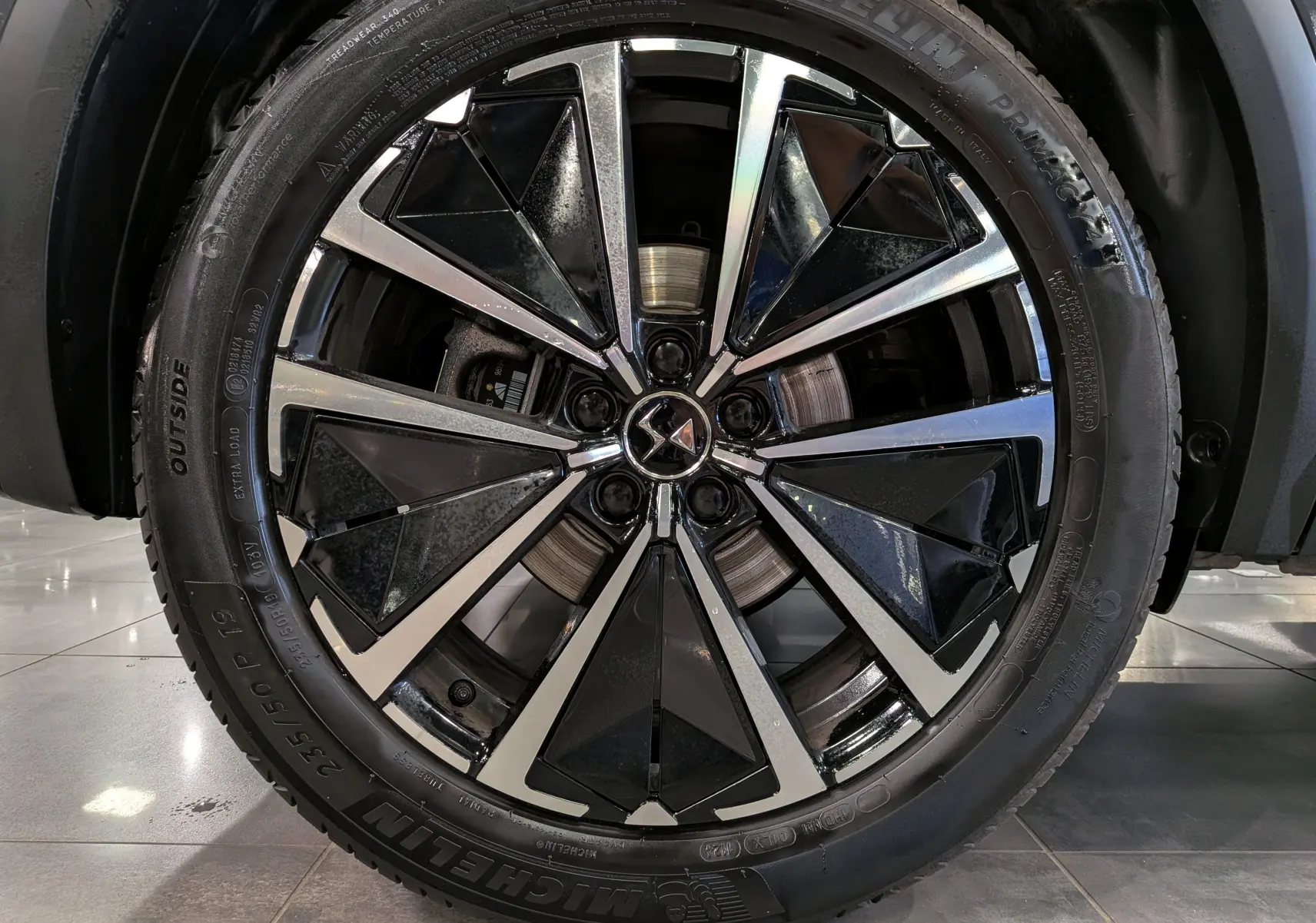 Gros plan sur la jante bi-ton noire et argentée du DS7 BlueHDi 130 gris, mettant en valeur le logo DS au centre.
