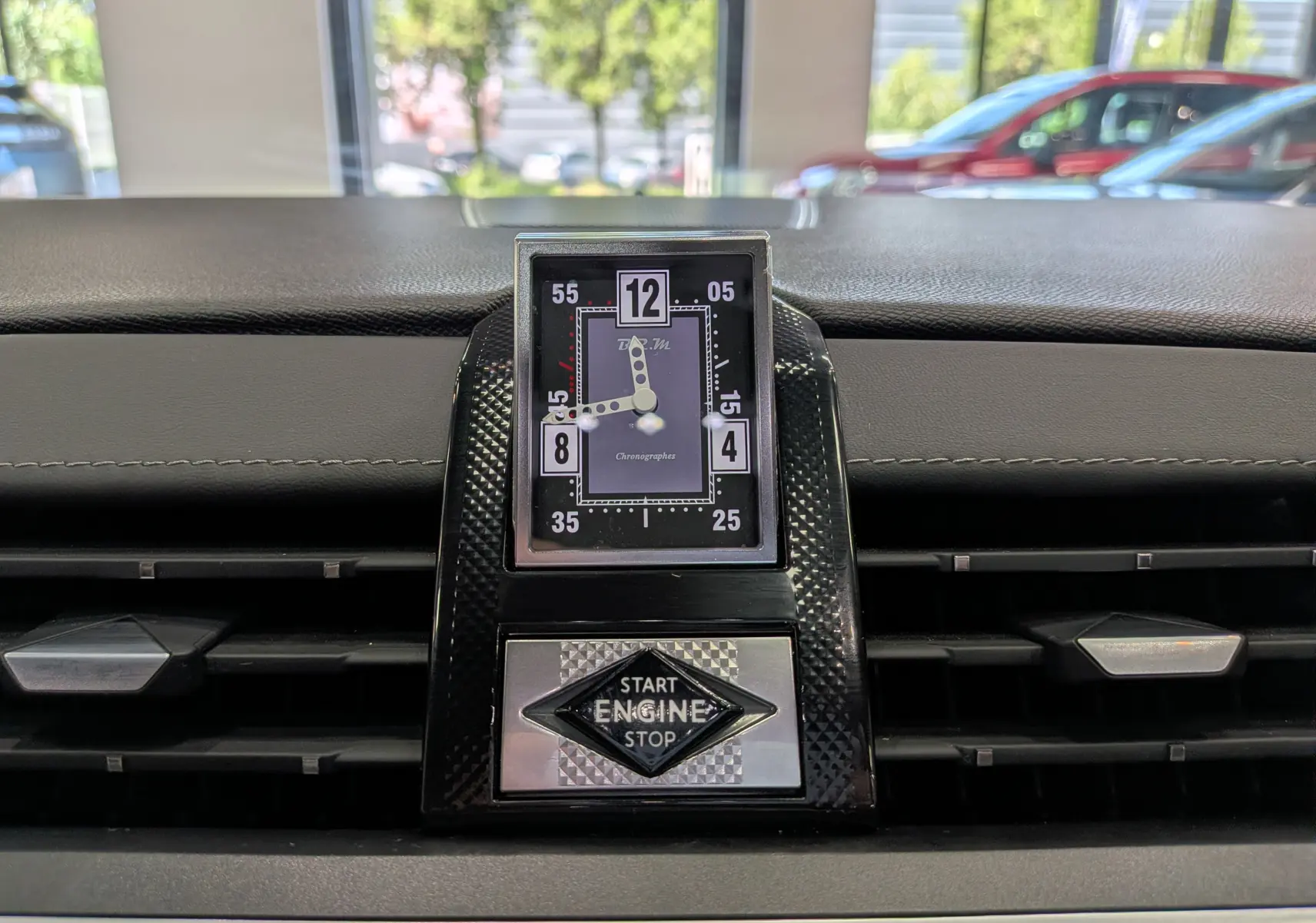Gros plan sur l'horloge analogique et le bouton start/stop du tableau de bord du DS7 gris 2024.