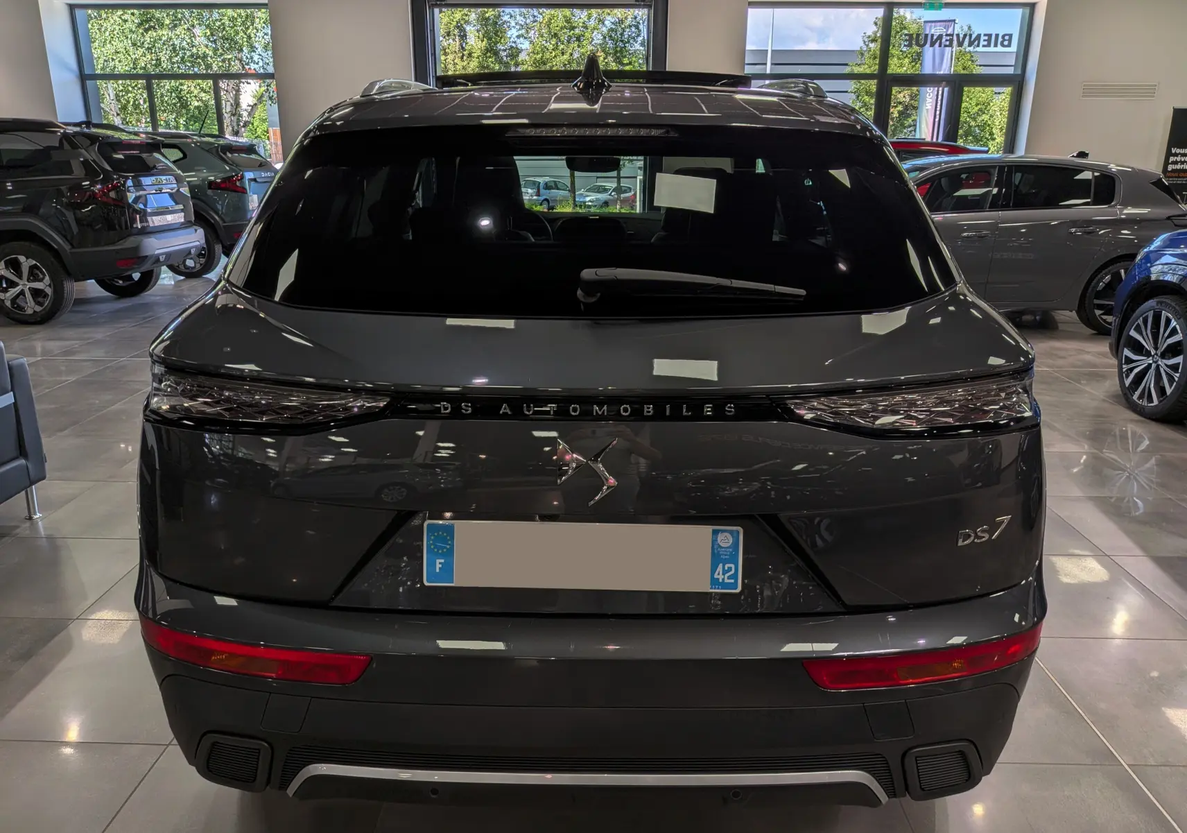 Vue arrière d'un DS7 gris 2024 dans un showroom, avec feux arrière étirés et logo DS centré sur le hayon.