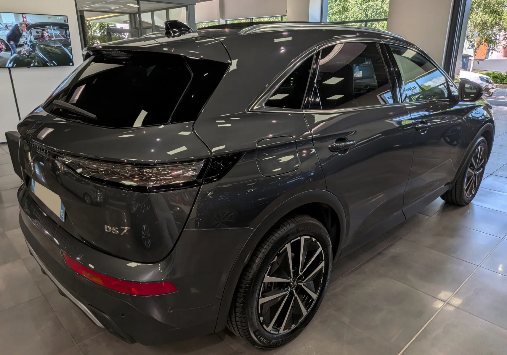 Vue 3/4 arrière droite du SUV DS7 BlueHDi gris foncé, avec jantes bi-ton et vitres teintées en showroom.
