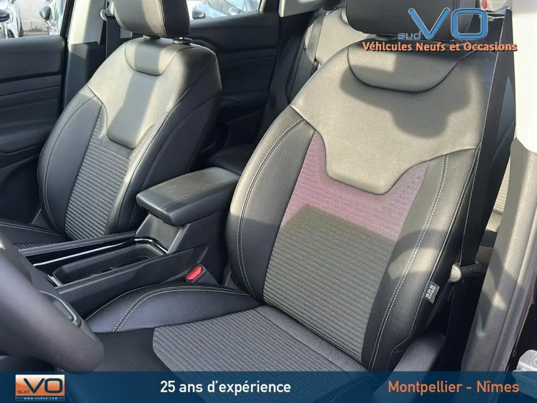 Gros plan sur les sièges avant en tissu et cuir noir du Jeep Compass 2024 avec accoudoir central visible.