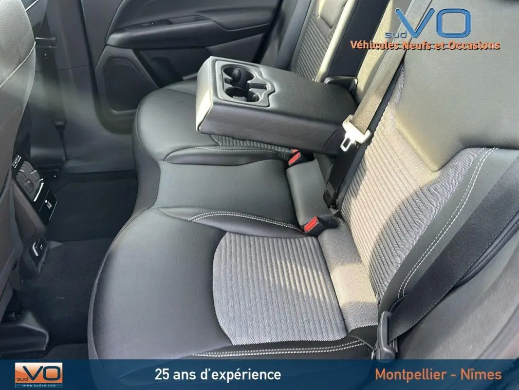 Vue intérieure du siège arrière droit du Jeep Compass noir 2024 avec accoudoir central relevé et ceintures visibles.