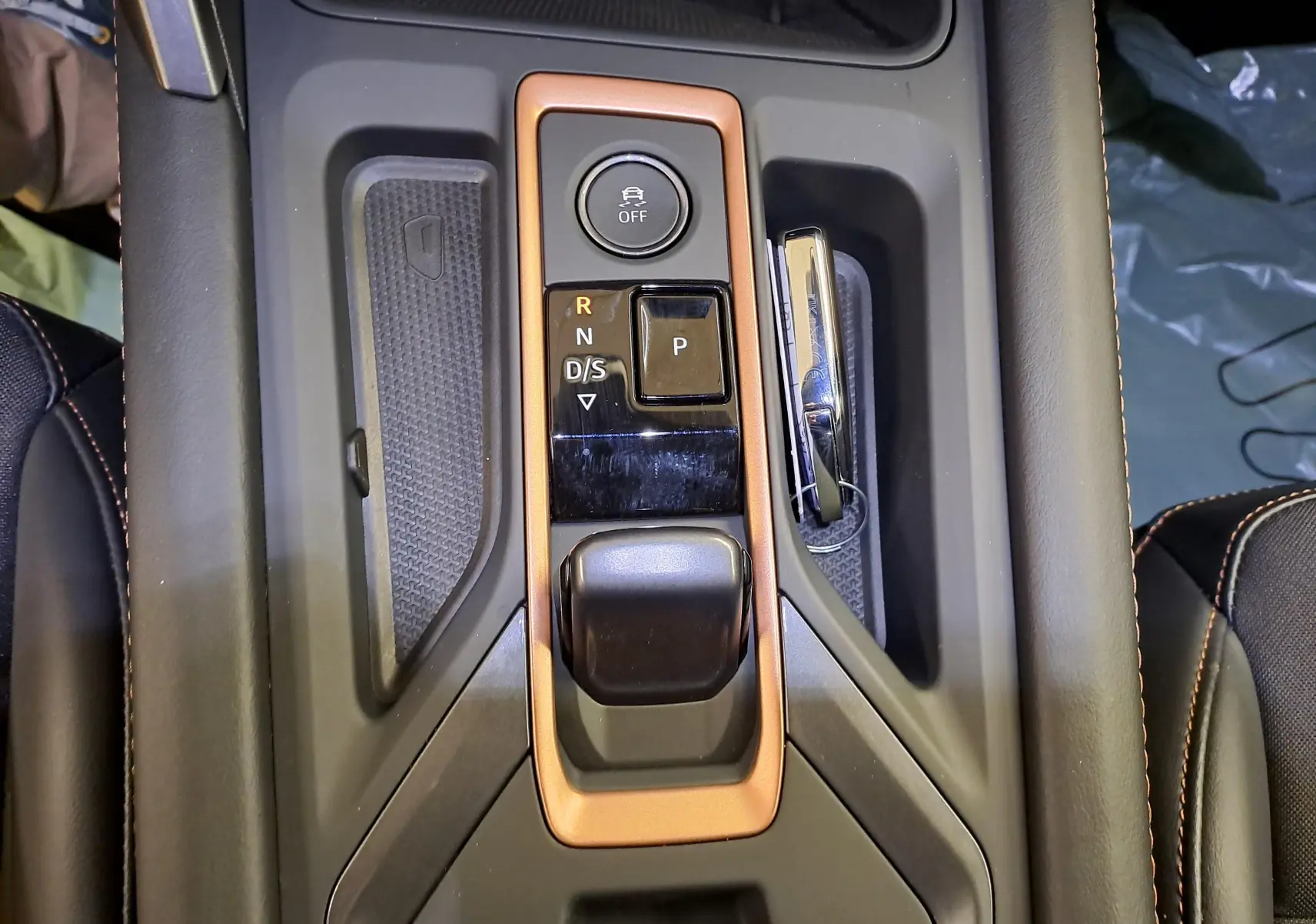 Vue rapprochée de la console centrale de la CUPRA Leon Ph.2 avec levier de boîte auto entouré d’un cadre cuivré.