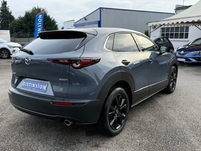 Vue 3/4 arrière droite d'un Mazda CX-30 2024 Polymetal Grey avec jantes noires et vitres teintées.