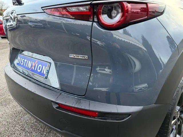 Vue arrière droite du Mazda CX-30 2024 en gris Polymetal avec feu rond distinctif et logo SKYACTIV visible.