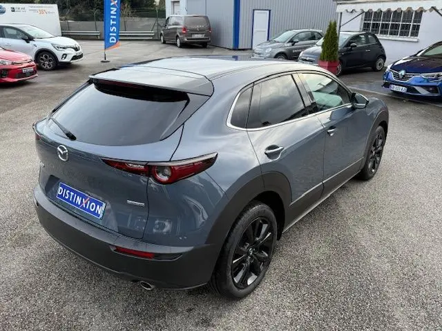 Vue 3/4 arrière droite d'un Mazda CX-30 2024 gris Polymetal avec jantes noires et vitres teintées.