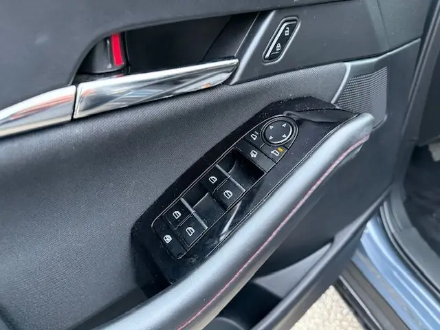 Vue intérieure côté conducteur du Mazda CX-30 2024 en Polymetal Grey, montrant la portière avec commandes et garniture noire.