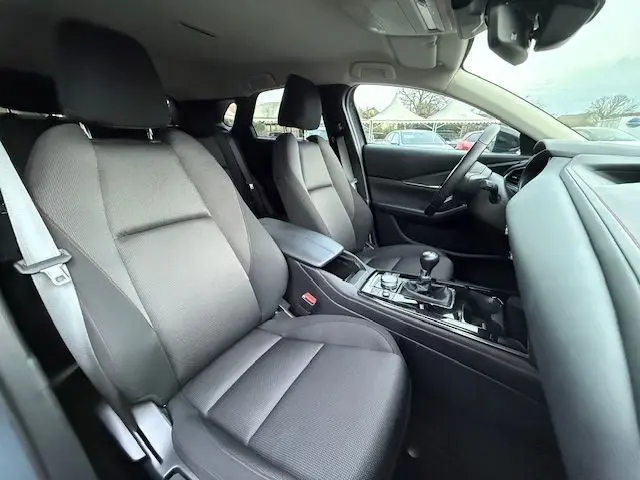 Intérieur avant du Mazda CX-30 2024 en gris, vue côté droit montrant sièges tissu et levier de vitesses manuel.