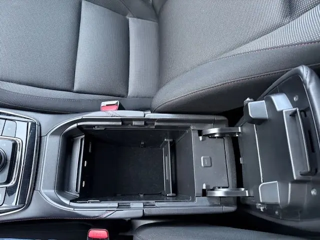 Vue plongeante sur la console centrale ouverte du Mazda CX-30 2024, intérieur tissu gris avec surpiqûres rouges.