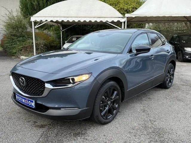 Vue 3/4 avant droite d’un Mazda CX-30 2024 Polymetal Grey avec jantes noires et calandre noire distinctive.