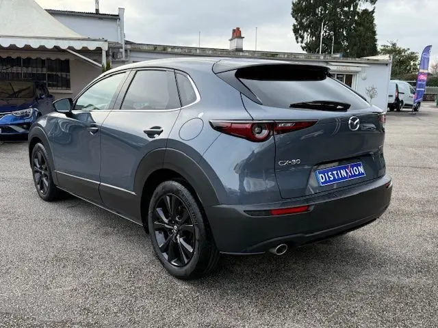 Vue 3/4 arrière droite du Mazda CX-30 2024 Polymetal Grey avec jantes noires et feux arrière fins distinctifs.
