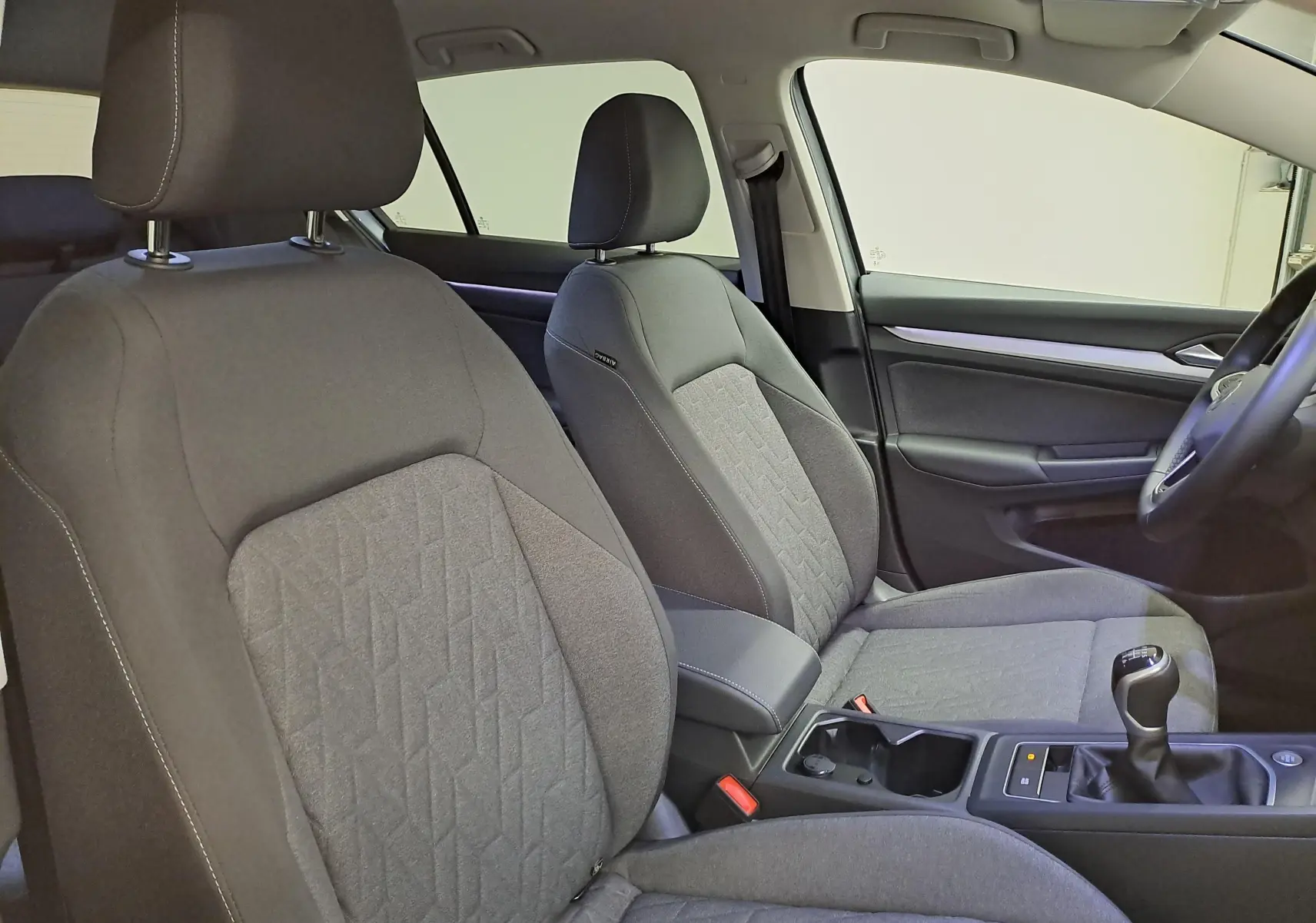 Vue intérieure côté conducteur de la Volkswagen Golf 1.5 TSI 116 BVM6 VW Edition avec sièges tissu gris et levier de vitesse manuel.