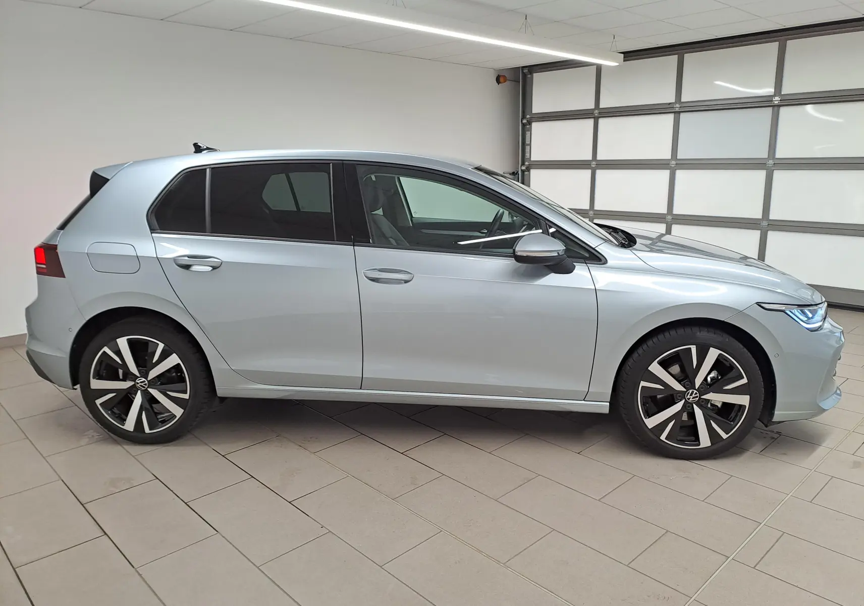 Vue de profil côté gauche d'une Volkswagen Golf 1.5 TSI 116 BVM6 VW Edition argent Dolomite avec jantes alliage 18 pouces.