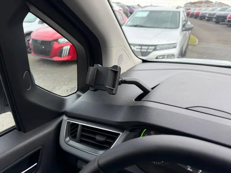 Vue intérieure côté gauche du tableau de bord noir du Nissan Townstar blanc minéral 2024 avec support téléphone fixé près de la fenêtre.