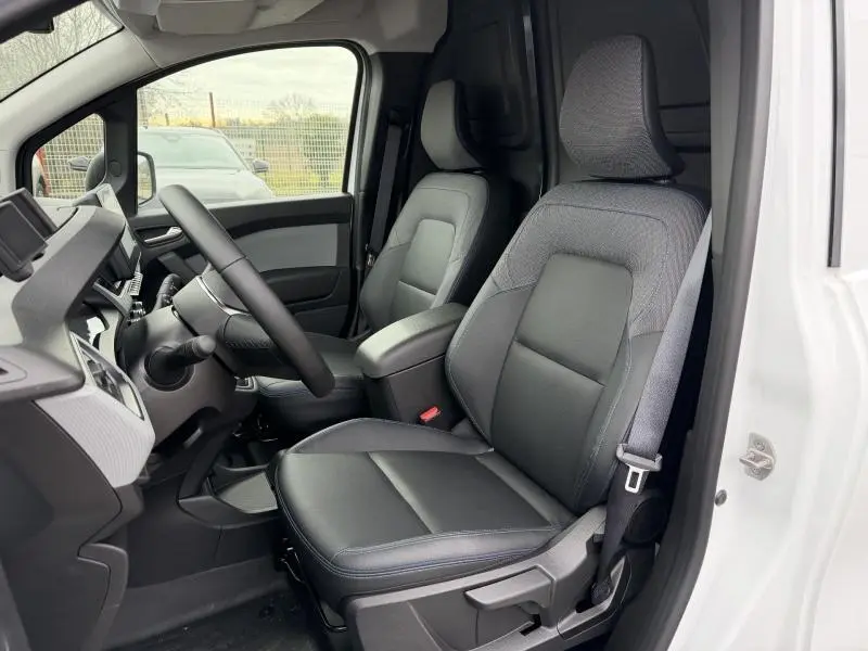 Vue intérieure côté conducteur du Nissan Townstar blanc minéral 2024, sièges en cuir noir avec surpiqûres bleues.