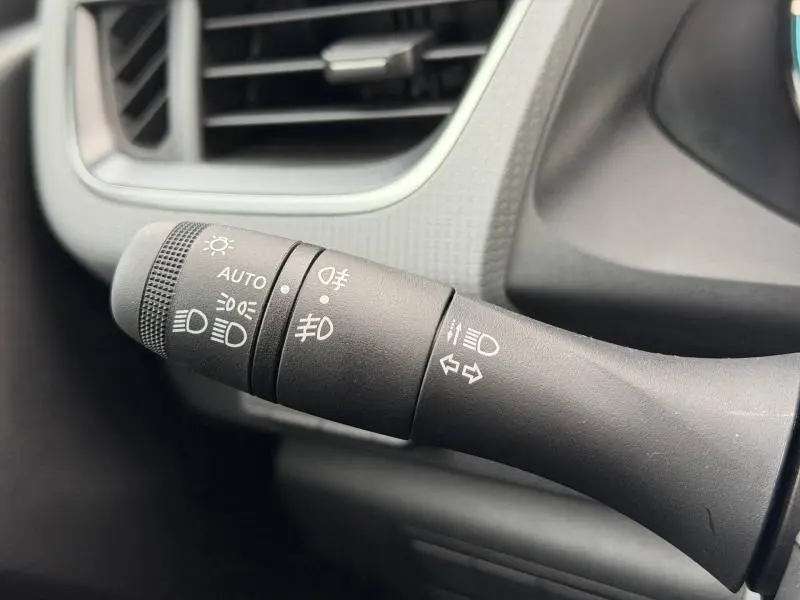 Gros plan sur la commande des phares et clignotants du Nissan Townstar blanc Minéral, côté gauche du volant.