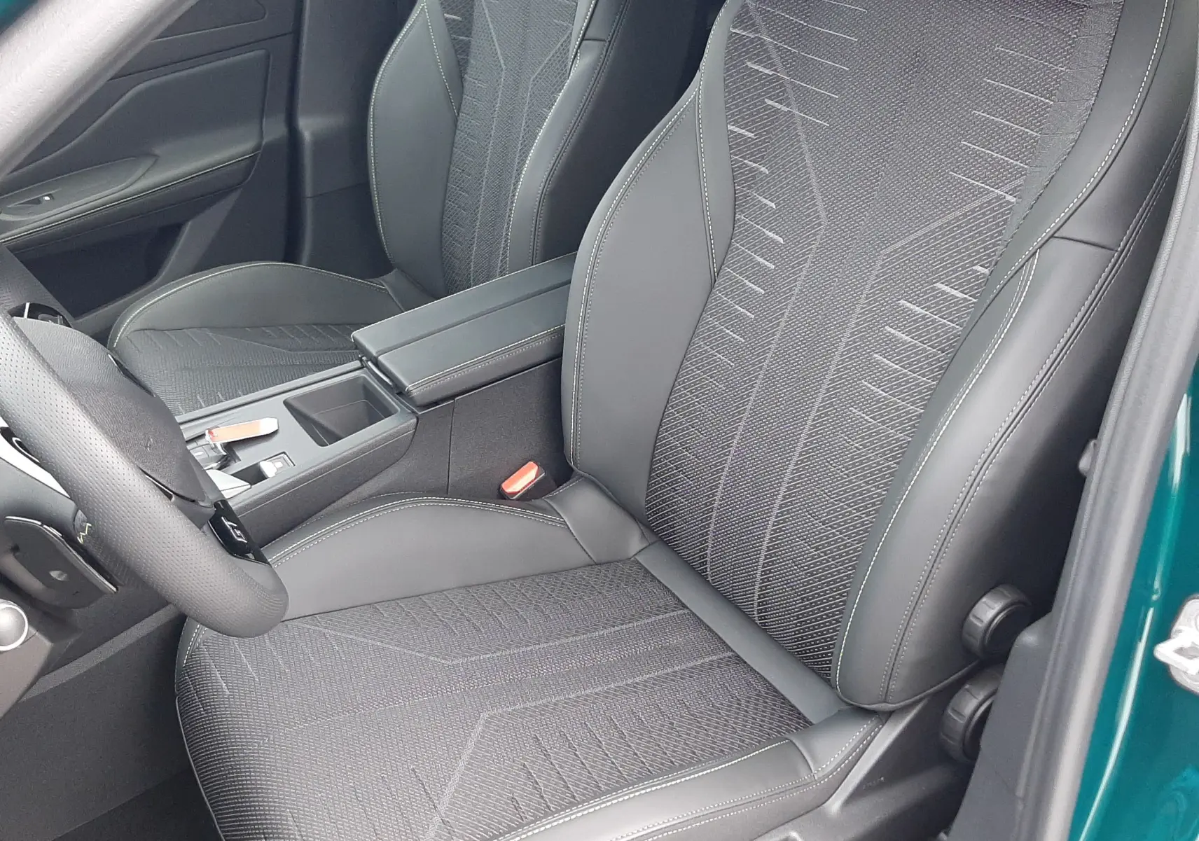 Vue intérieure côté conducteur de la Peugeot 308 1.2 Hybrid 145ch GT bleu Lagoa, sièges en tissu et cuir noir avec surpiqûres.