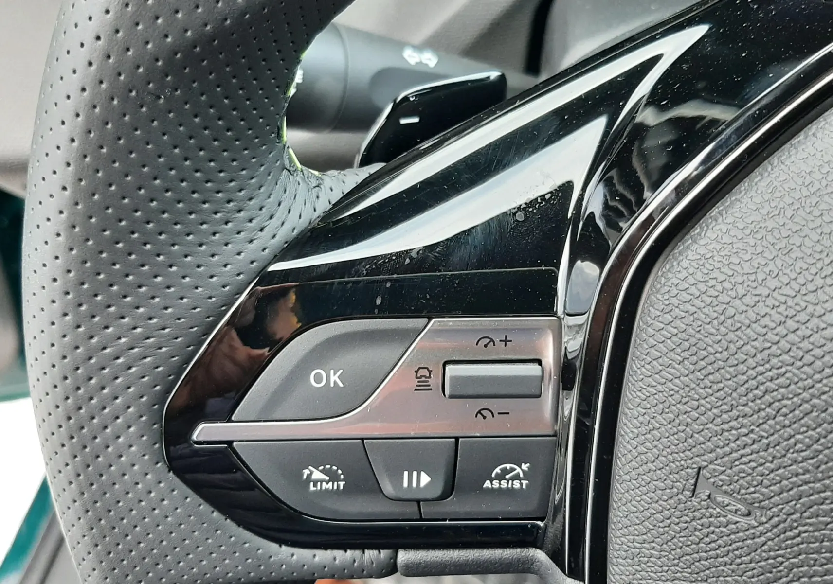 Gros plan sur les commandes au volant côté gauche en cuir perforé noir du Peugeot 308 Hybrid 2026.