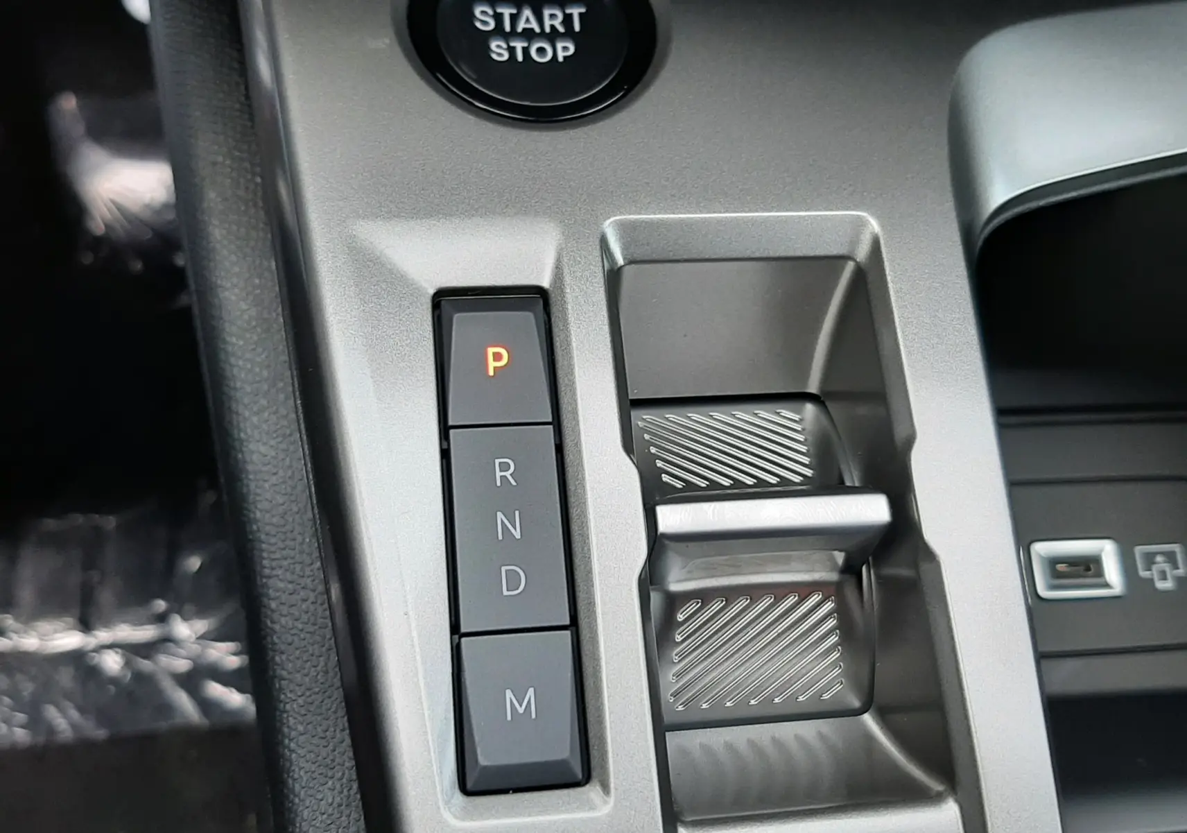 Gros plan intérieur sur la console centrale de la Peugeot 308 Hybrid 2026, avec boutons de boîte auto et bouton start/stop.