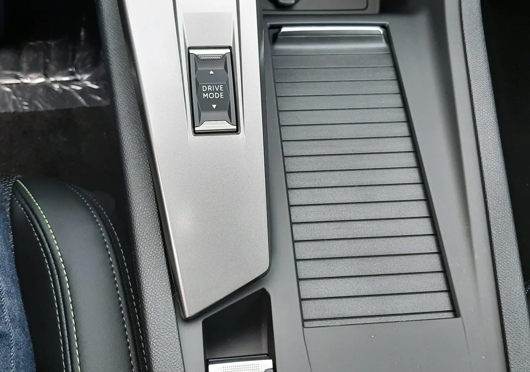 Vue rapprochée de la console centrale noire et grise avec bouton Drive Mode et frein à main électrique éclairé dans une Peugeot 308 hybride.