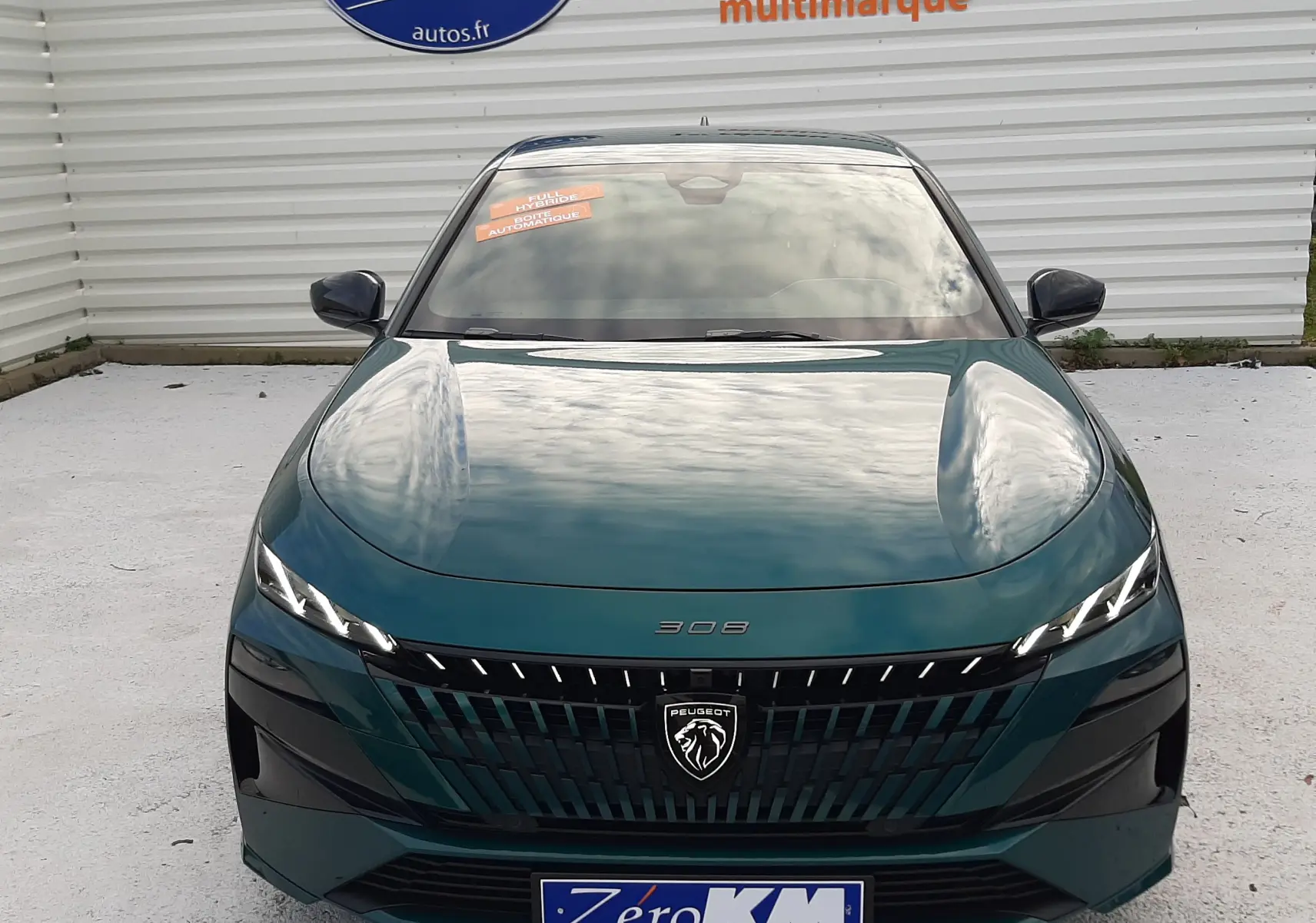 Vue frontale d'une Peugeot 308 1.2 Hybrid 145ch GT bleu Lagoa avec calandre noire et phares LED fins.
