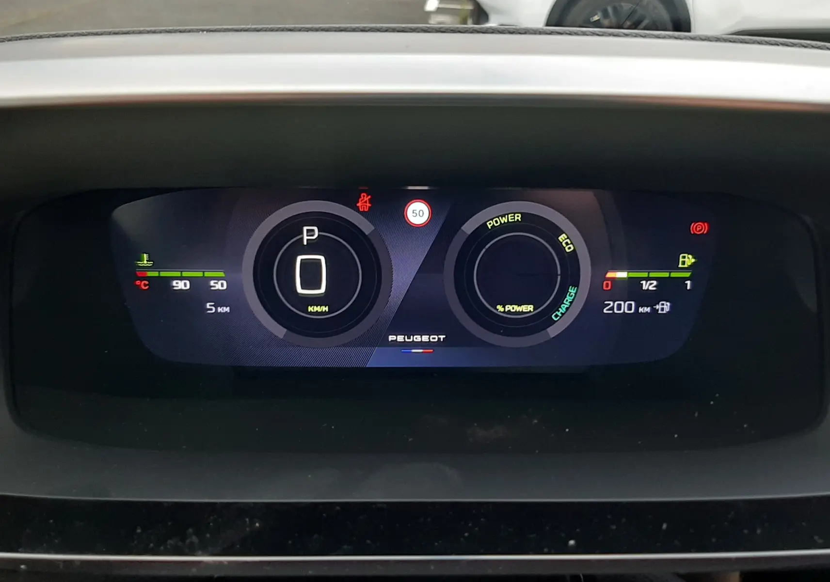 Tableau de bord numérique du Peugeot 308 hybride, affichant la vitesse à 0 km/h et l'autonomie restante.