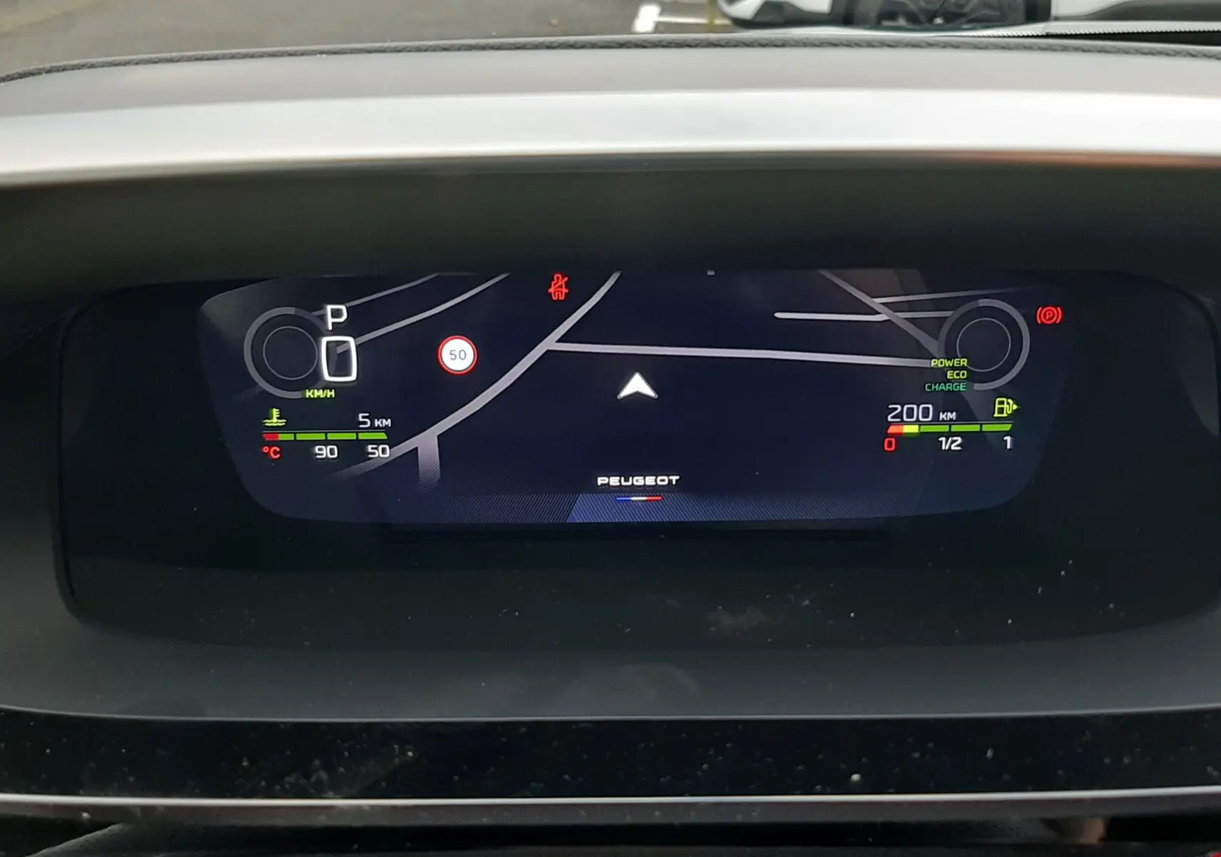 Affichage numérique du tableau de bord de la Peugeot 308 hybride, indiquant la vitesse, autonomie et mode de conduite.