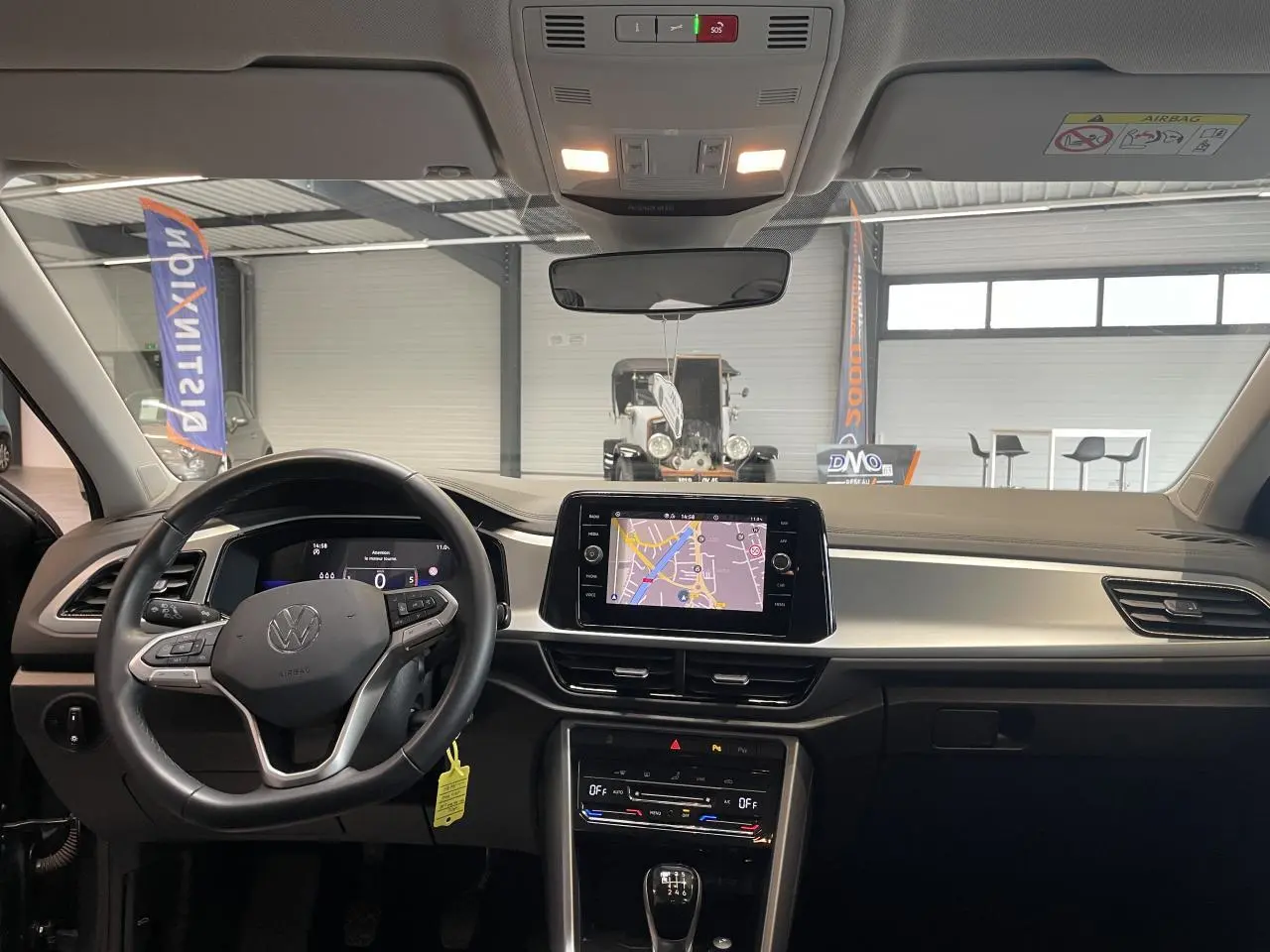 Vue intérieure frontale du tableau de bord du Volkswagen T-Roc 2025 gris Indium avec écran tactile et volant multifonction cuir.