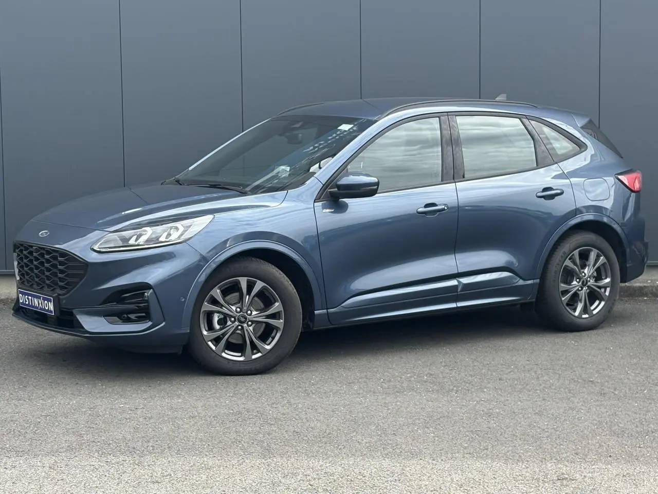 Ford Kuga gris azur en vue de profil côté gauche, avec jantes alliage et calandre noire distinctive.