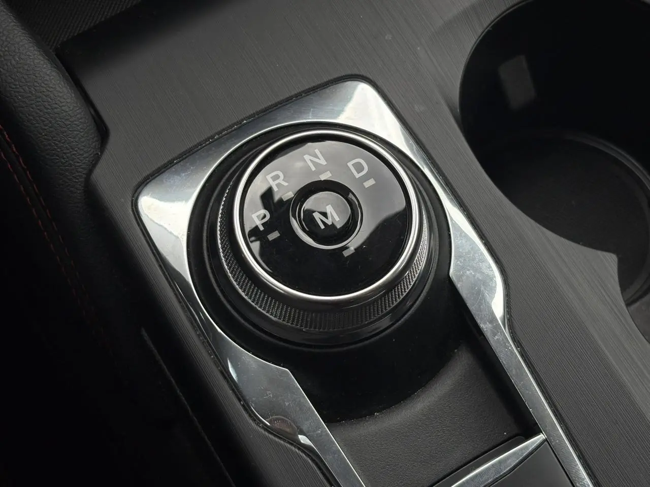 Sélecteur rotatif de boîte automatique noir et chrome dans la console centrale du Ford Kuga gris Azur 2023, finition ST-Line.