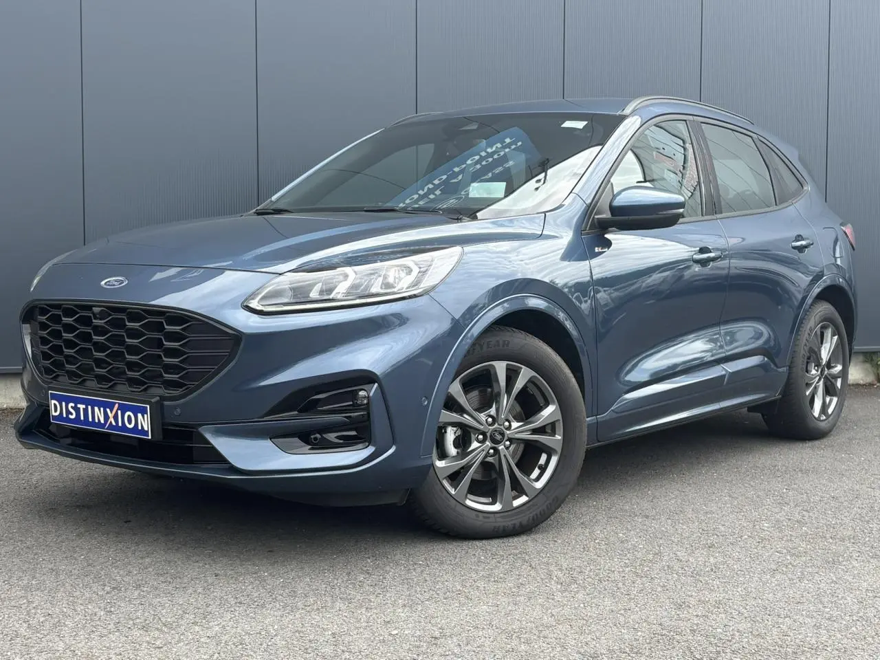 Ford Kuga 2.0 EcoBlue gris azur en 3/4 avant droit, avec calandre noire et jantes alliage 18 pouces.