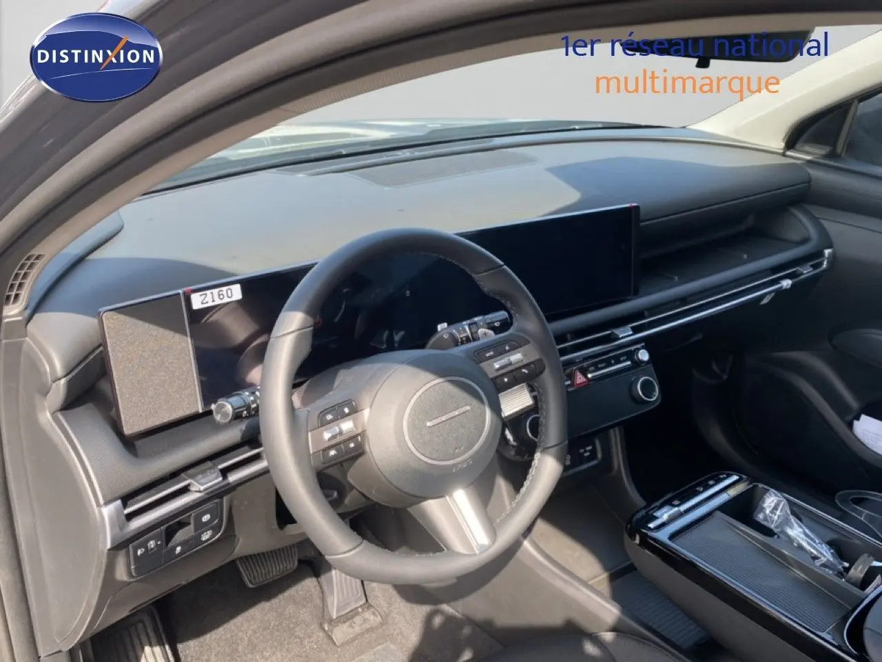 Vue intérieure côté conducteur du Hyundai Tucson 2026, tableau de bord moderne avec écran large et volant multifonction noir.