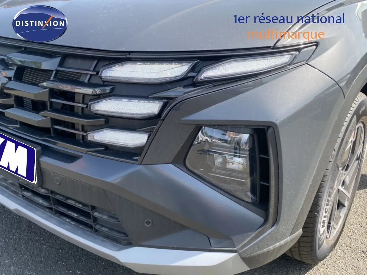 Gros plan sur l’avant droit du Hyundai Tucson gris Ecotronic Metal, mettant en valeur la calandre et les phares LED distinctifs.