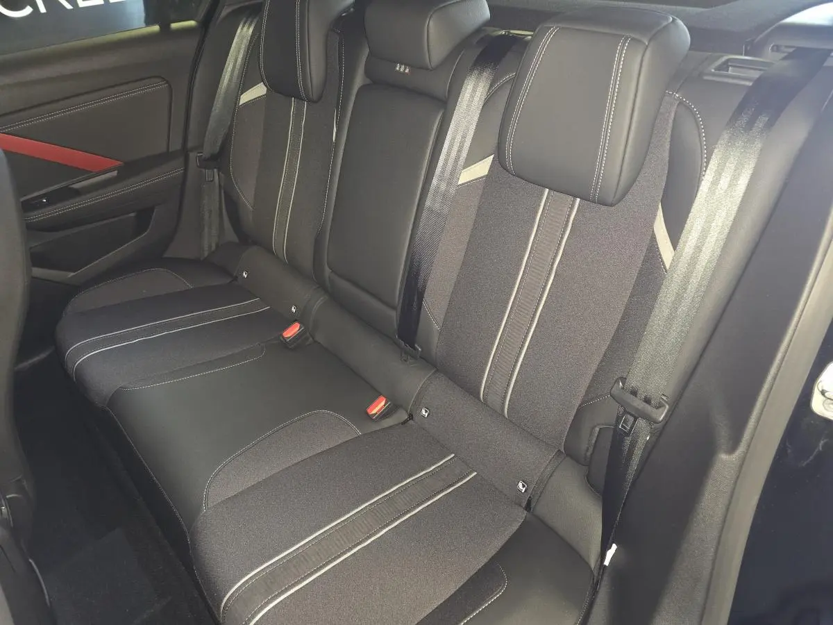 Vue intérieure de la banquette arrière noire de l'Opel Astra Hybrid 2024 avec ceintures et appuie-têtes intégrés.