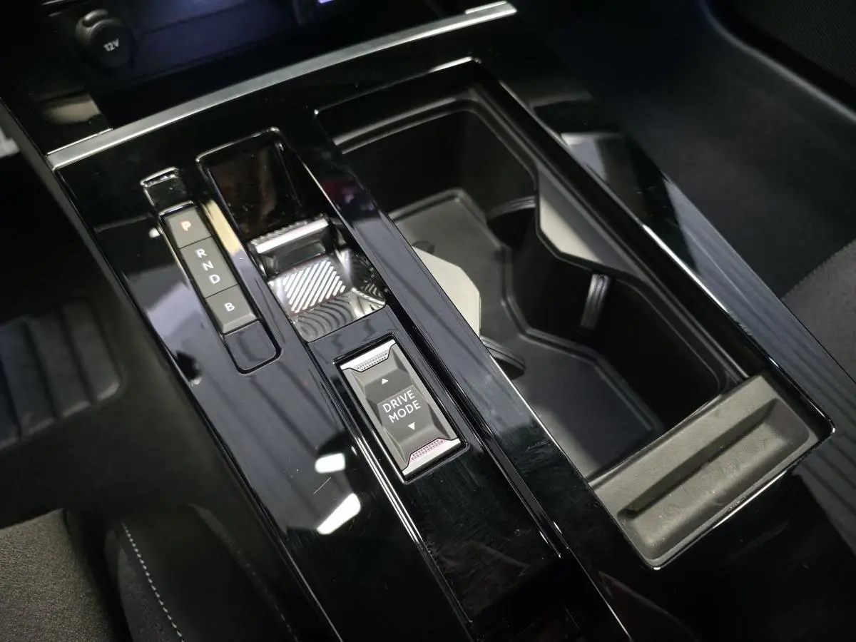 Gros plan sur la console centrale noire brillante de l’Opel Astra Hybrid 2024 avec sélecteur de mode de conduite.