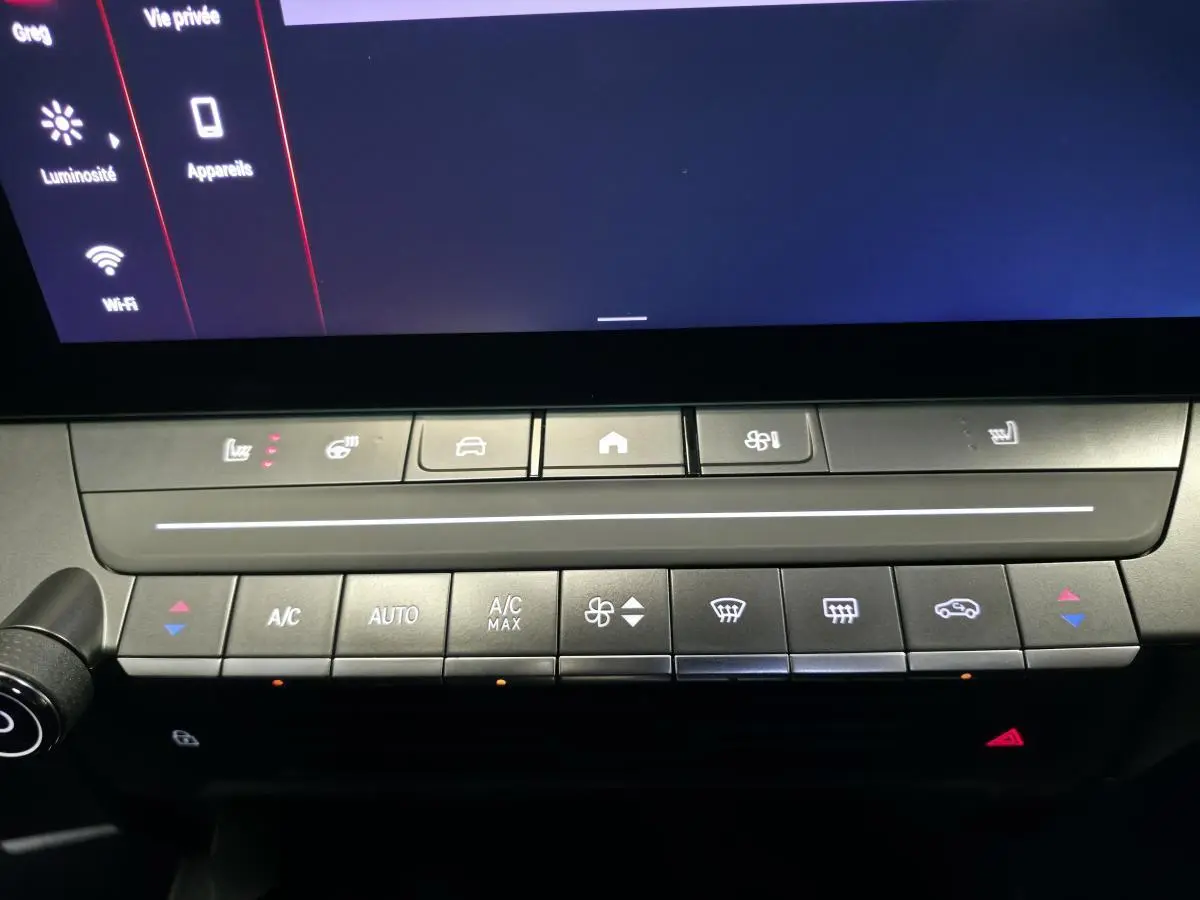 Détail de la console centrale de l’Opel Astra Hybrid 2024 avec commandes climatisation et écran tactile noir.
