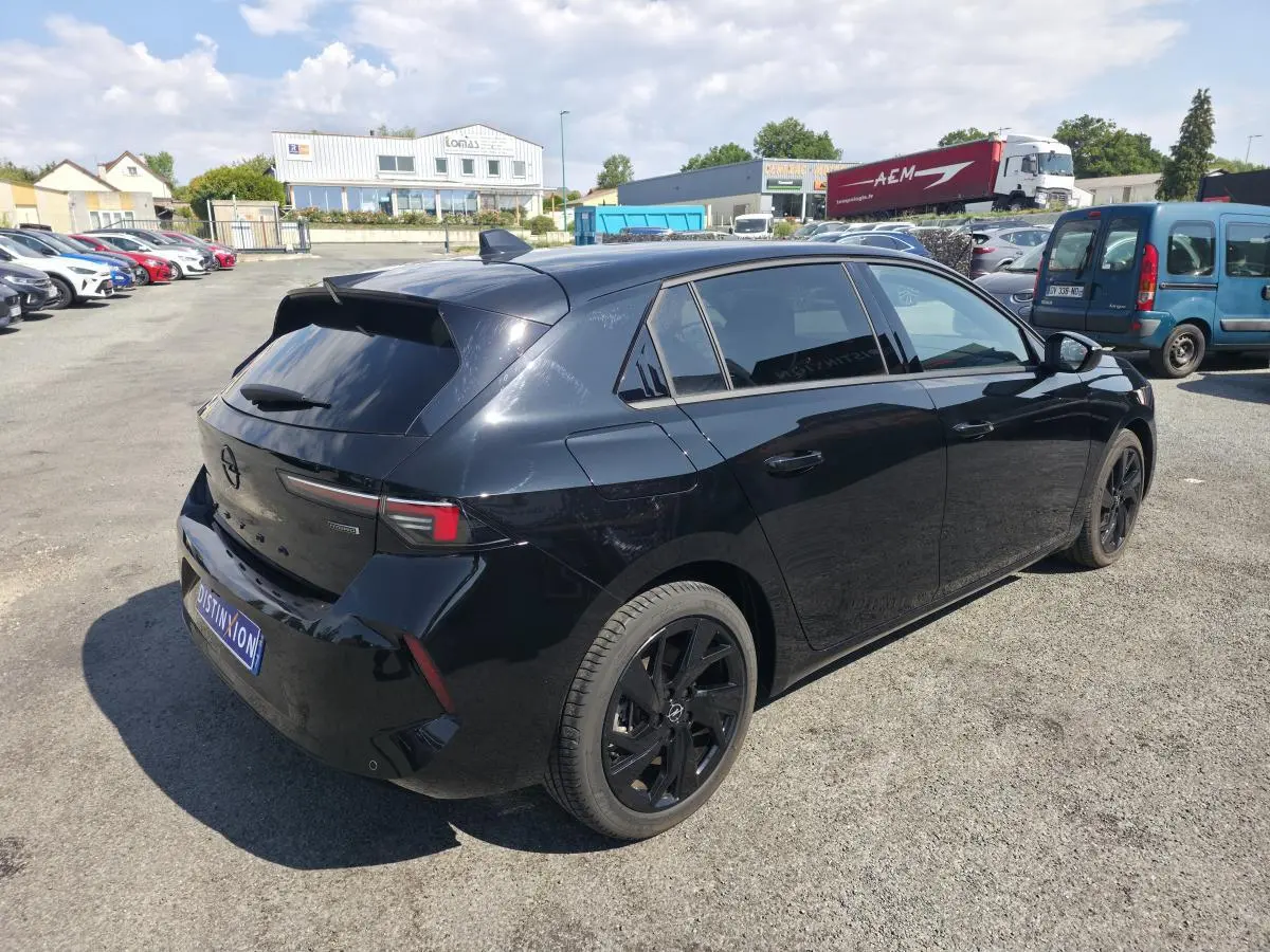 Opel Astra Hybrid 2024 noire en 3/4 arrière droit avec jantes alliage noires et vitres surteintées.