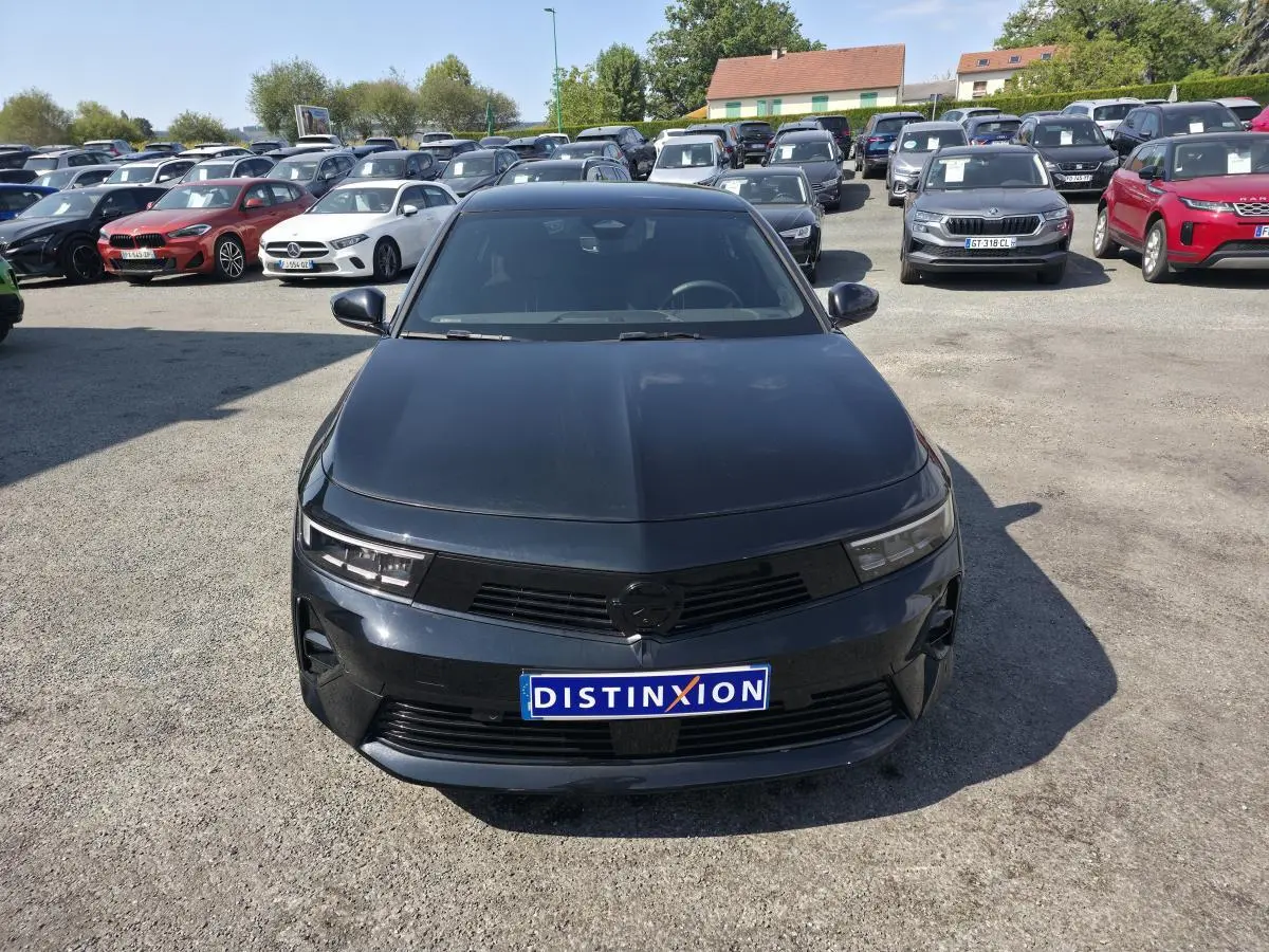 Vue avant d'une Opel Astra Hybrid 2024 noire avec calandre noire et jantes alliage 17 pouces sur parking.