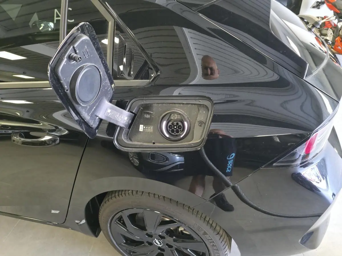 Prise de recharge ouverte sur le côté gauche arrière d’une Opel Astra Hybrid noire avec jantes alliage noires.